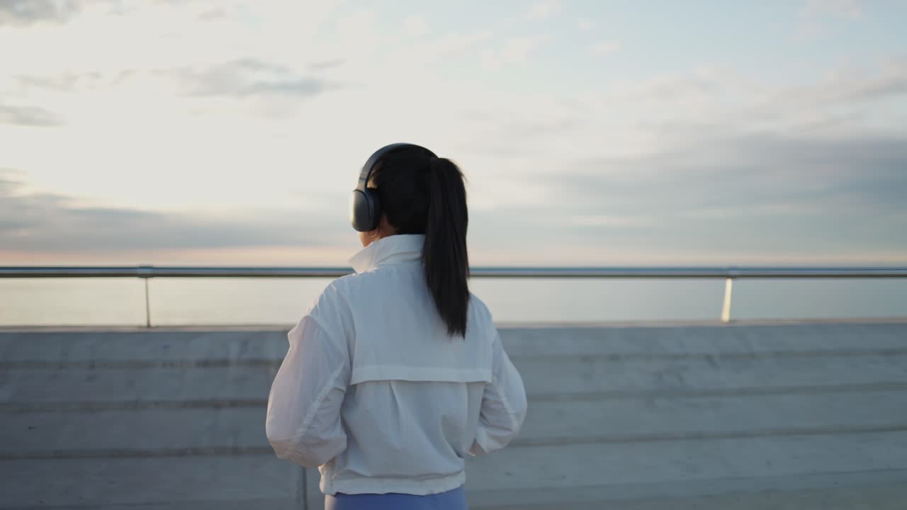 戴耳机的年轻亚洲女性在海边散步休憩