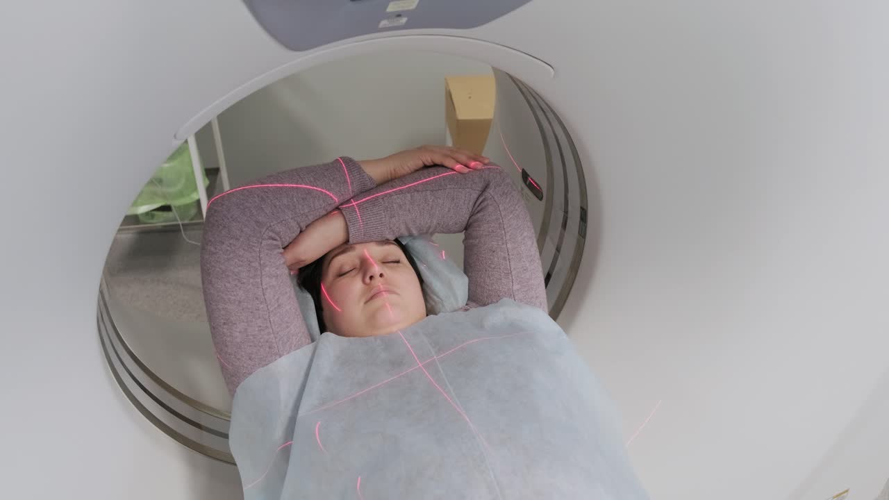 mujer acostada en el escáner de ct o mri durante la máquina de imágenes de su cuerpo, se enciende los rayos infrarrojos y la paciente pasa a través del círculo, grúa disparada de abajo hacia arriba, interior de la habitación, escena activa.
