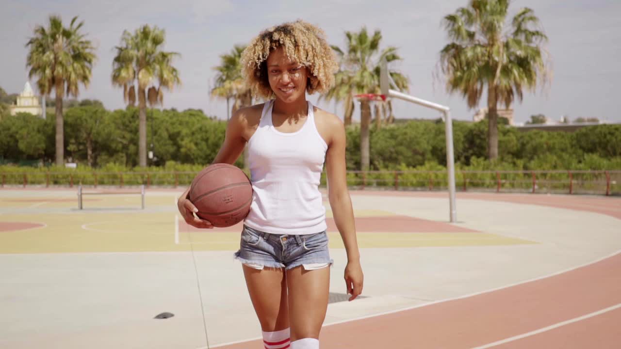 Giovane donna attraente in posa con un pallone da basket.