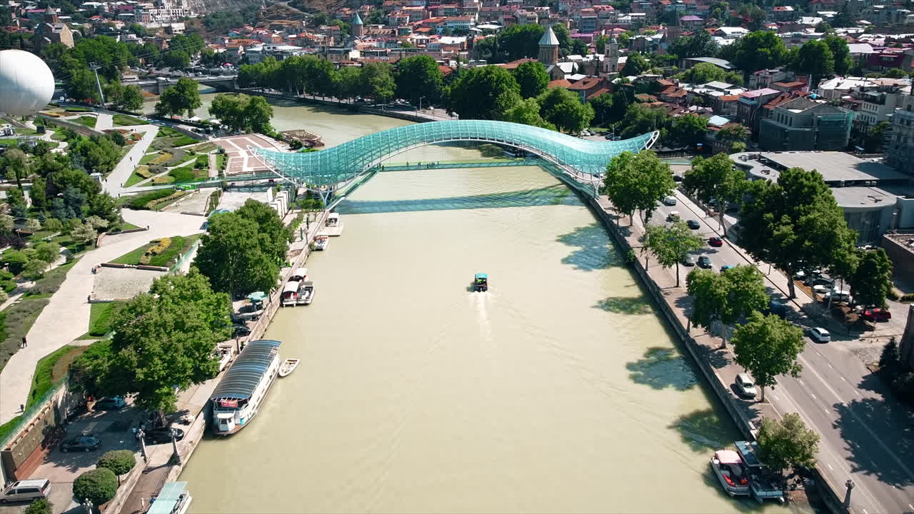 Aerial drone view of the city. Multiple buildings, business center, a lot of greenery, Kura river, road with traffic. Tbilisi, Georgia