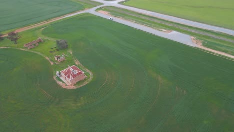 Blick-Von-Oben-Nach-Unten-Auf-Ein-Altes-Backsteinhaus-Auf-Dem-Land,-Das-Endlose-Grüne-Felder-Freigibt,-Burra-Gehöft