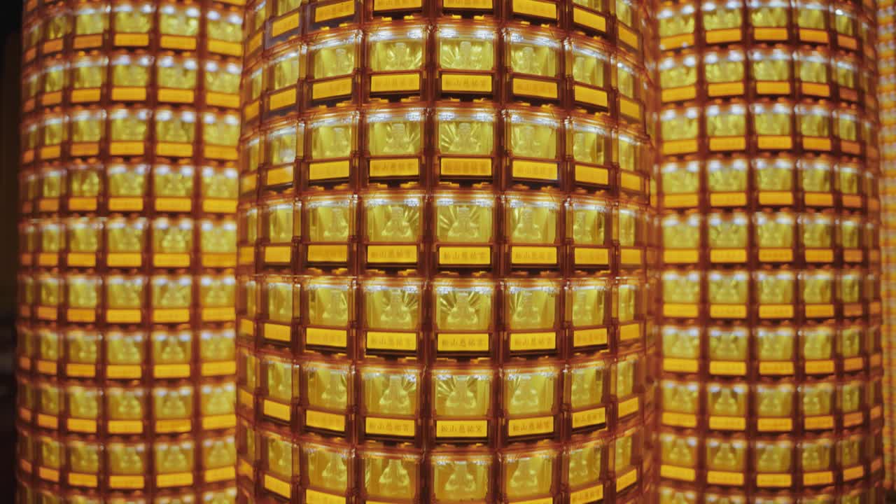A symmetrical close-up of golden Buddha statues glowing in individual illuminated niches at Ciyou Temple in Taiwan, symbolizing devotion, peace, and spiritual reverence in a sacred Buddhist space