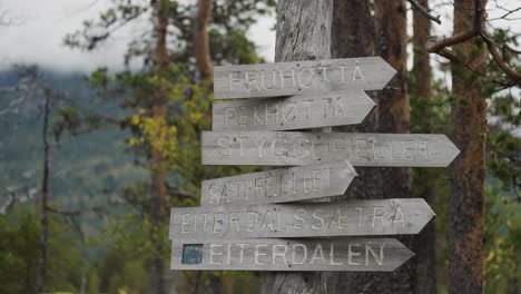 a rustic wooden signpost points in multiple directions, indicating different mountain trails and destinations.