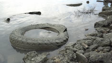 Old-abandoned-car-tire-at-coast.