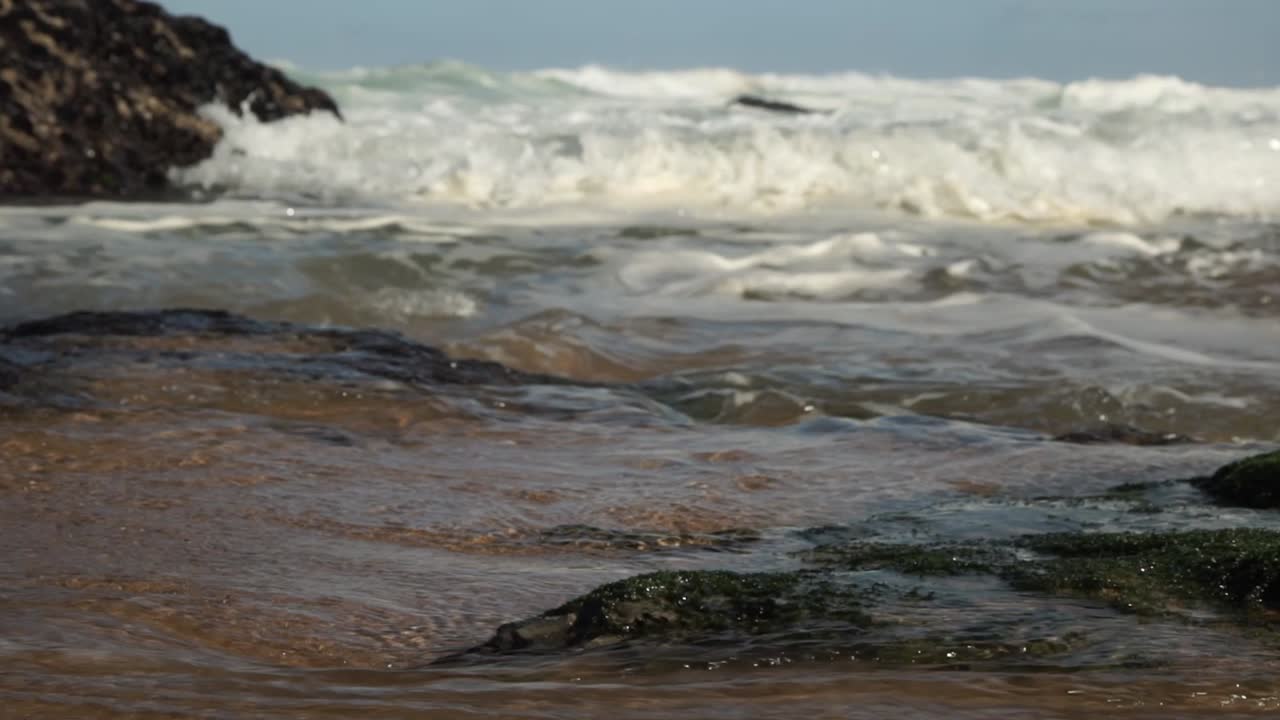 Fast moving ocean waves crashing onto rocky shore. Cresmina beach (Praia da Cresmina), Portugal.
