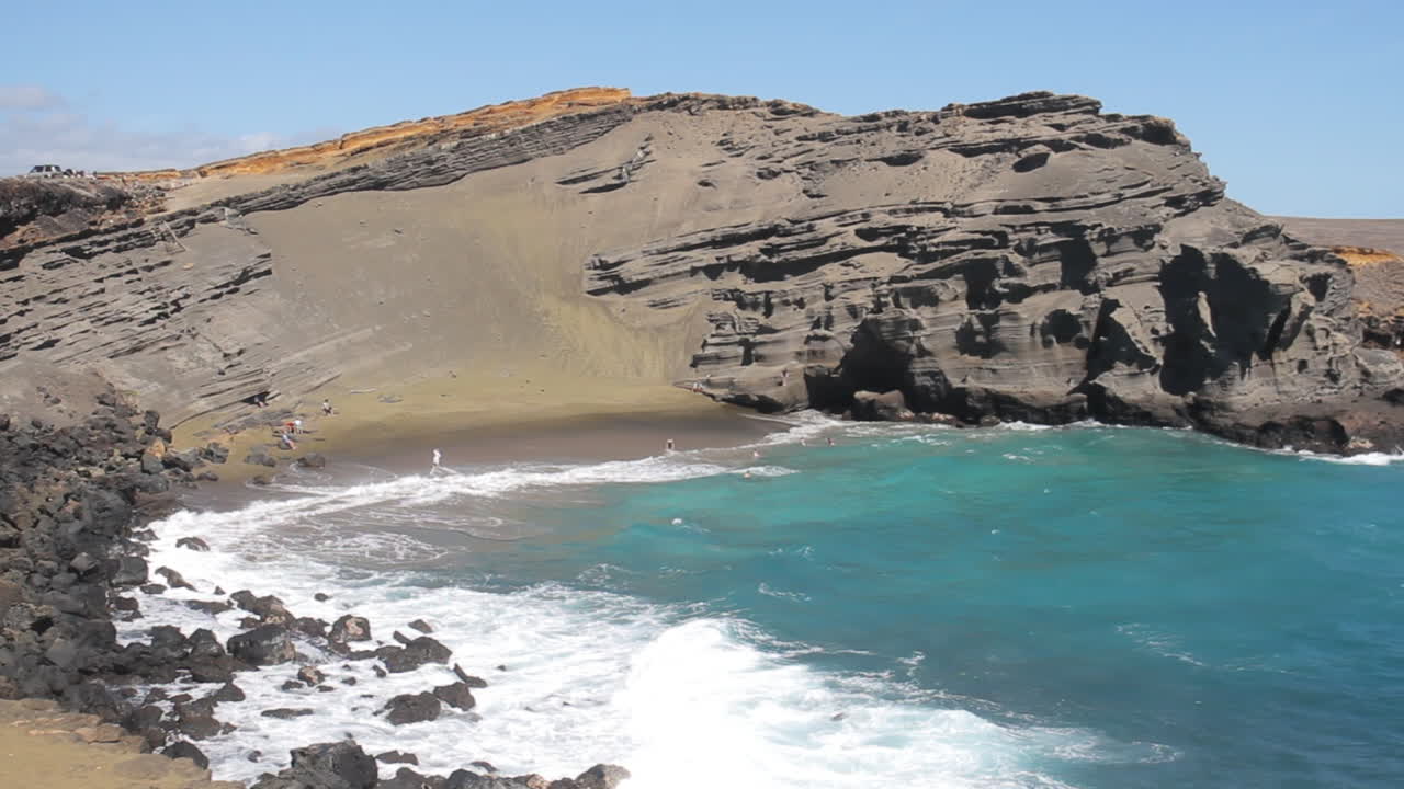 las olas chocan contra la costa en la playa de arena verde en hawaii