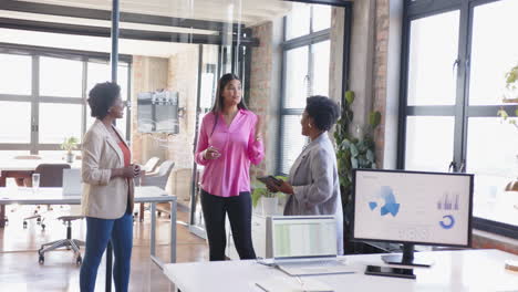 discussing project with digital devices, businesswomen collaborating in modern office