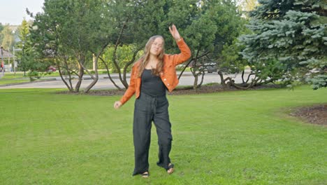 Young-girl-enjoying-moment,-dancing-in-slow-motion-in-green-urban-park