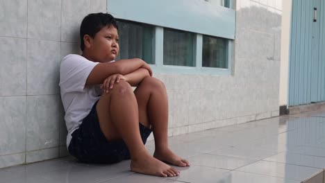 depressed boy sitting on the terrace floor