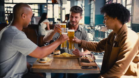 group of male friends meeting up in bar doing cheers with beer