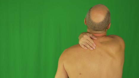 hombre frotando sus hombros con la mano derecha. vista trasera desnuda de cintura hacia arriba.
