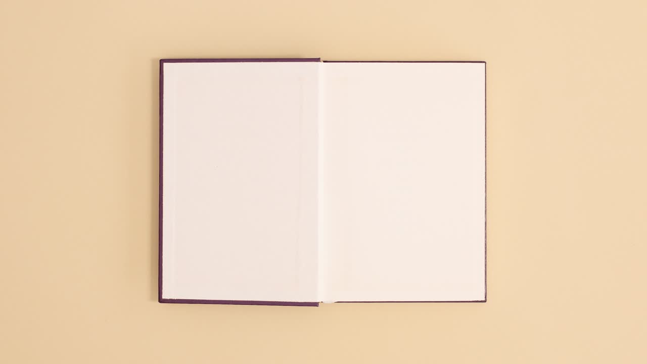 Purple hardcover vintage book appear and open with copy space on beige background. Stop motion flat lay