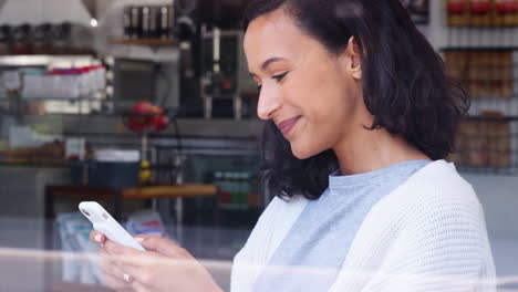 joven usando su teléfono inteligente en una cafetería