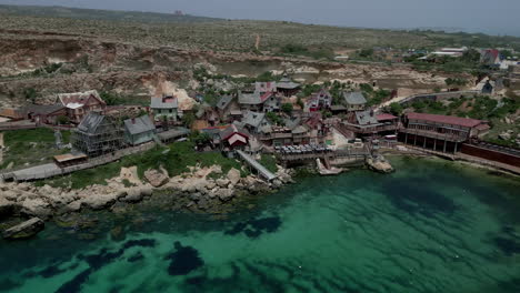 Vista-Aérea-Del-Pueblo-De-Popeye-Y-Mirador-En-La-Bahía-Del-Ancla-En-Mellieha,-Malta