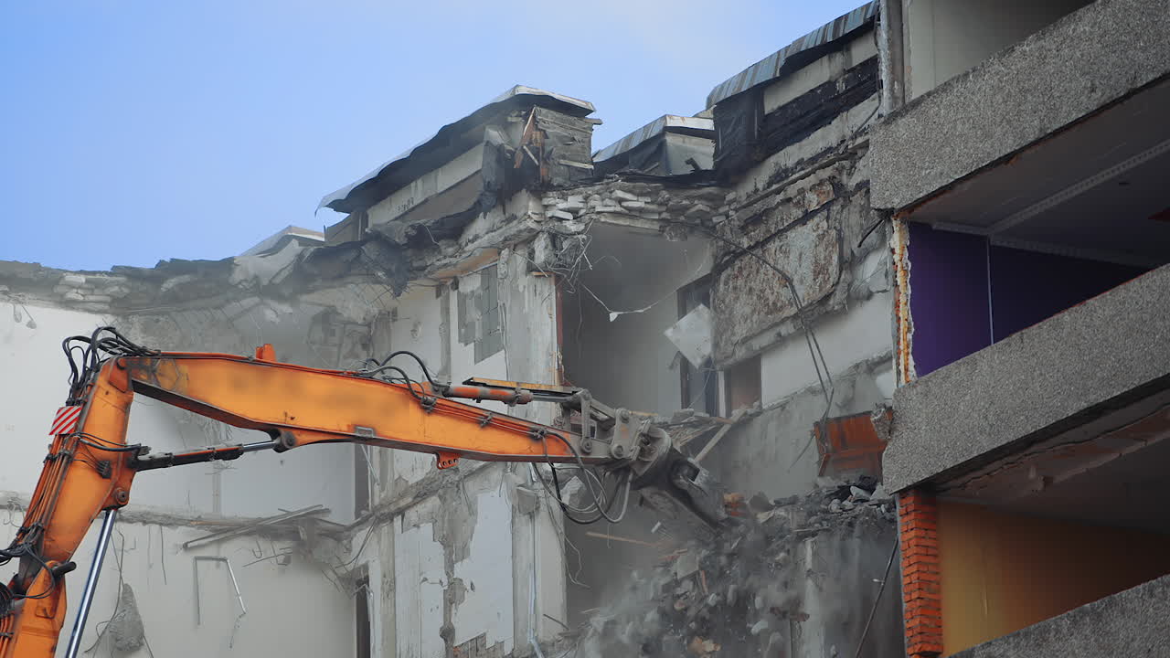 Powerful excavator claw dump the debris on the ground. Deconstruction site covering with the dust. Clear blue sky at the backdrop.