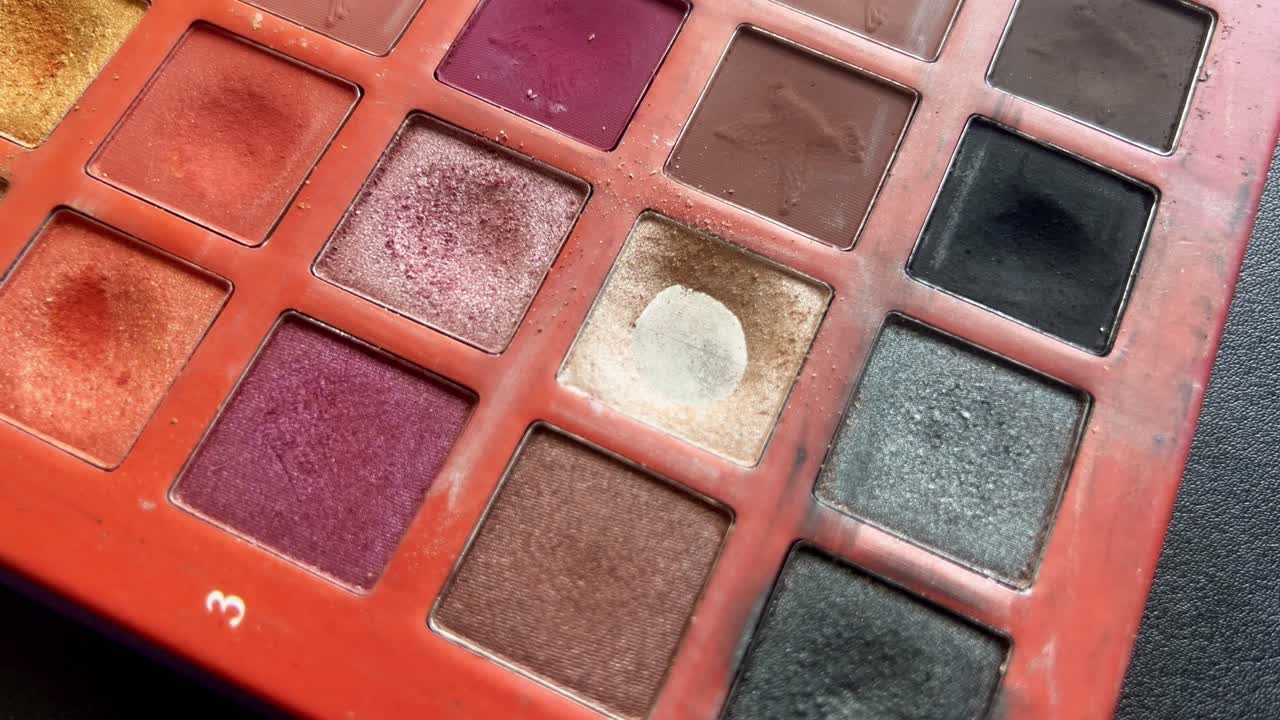 toma de primer plano estática de un pincel de maquillaje que se mezcla sobre una sombra de ojos de tono de piel en una paleta colorida