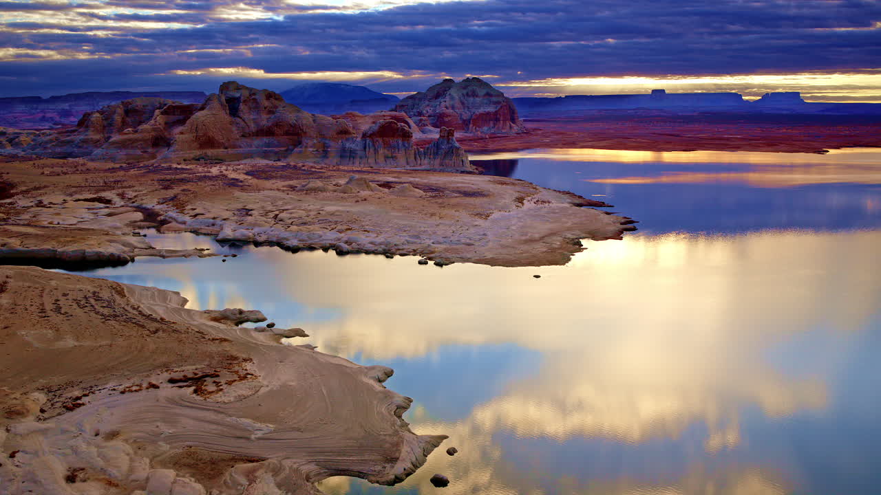 A dynamic drone shot capturing the vivid colors and dramatic textures of the Lake Powell desert region.