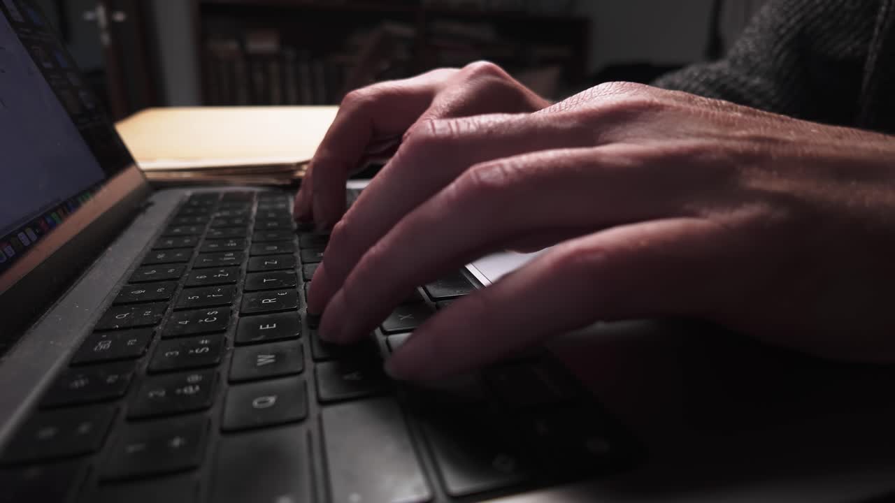 Man remote working from home typing on laptop keyboard in office SIDE VIEW