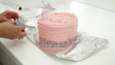 woman in bakery decorating cake with sugar sprinkles