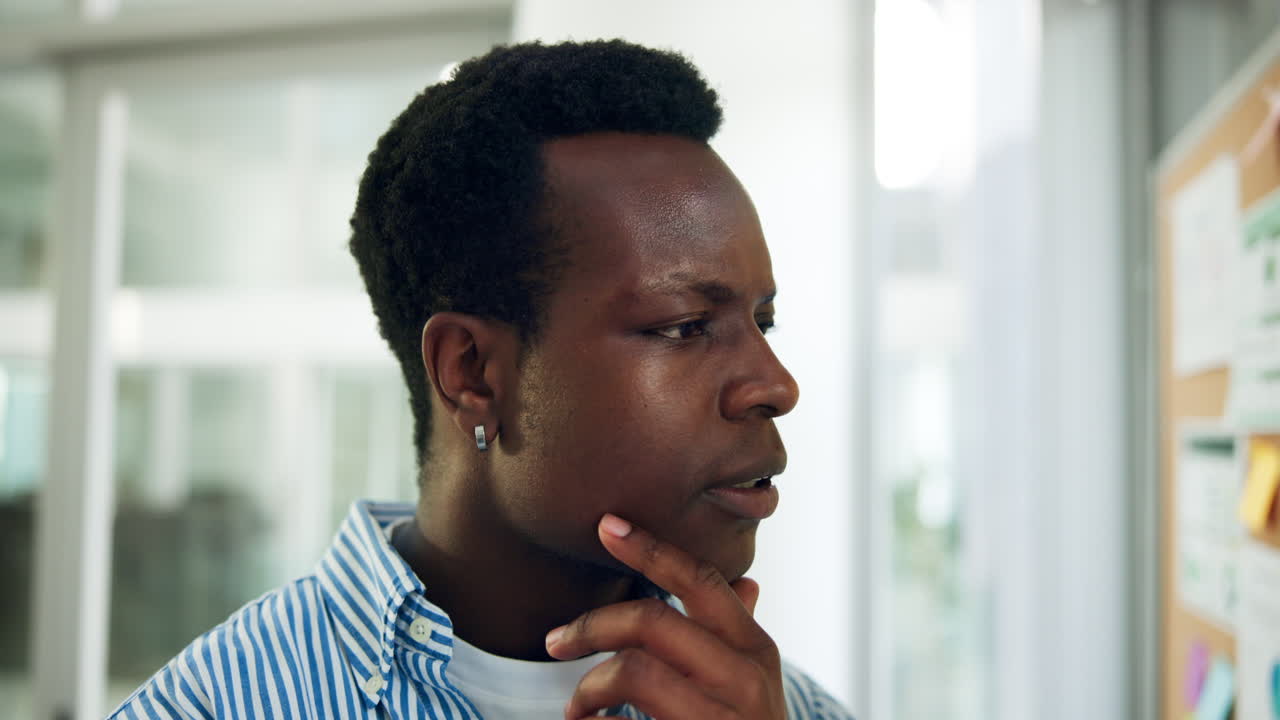 Young Black Man Thinking and Analyzing Notes on Cork Board