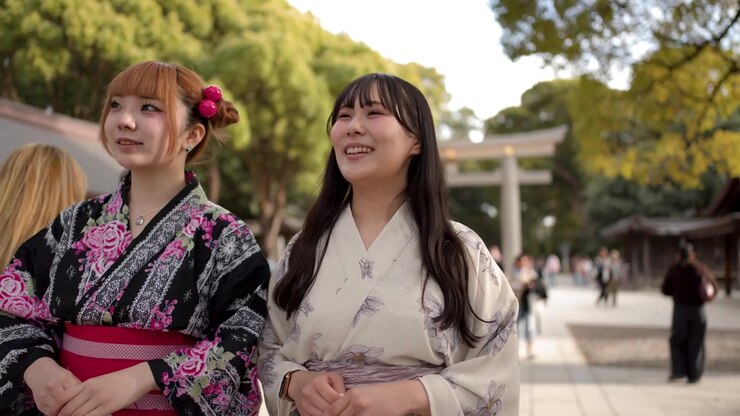 Due donne che indossano yukata tradizionali passeggiano nel cortile di un santuario shintoista in una giornata di sole.