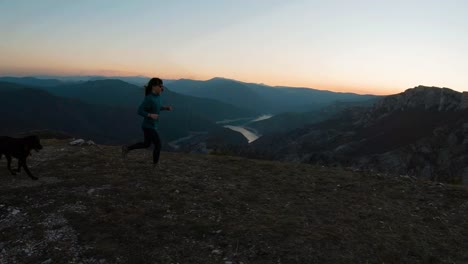 young girl running with a labradot dog on a mountain at sunset during autumn