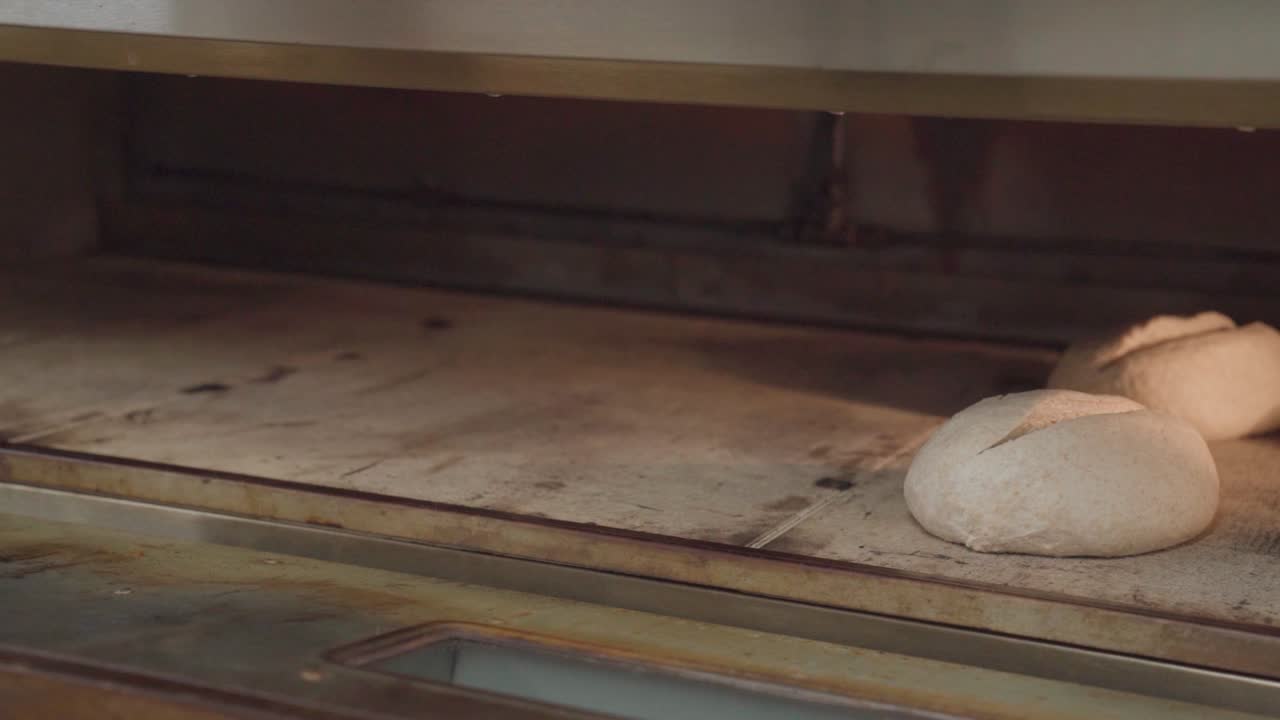 Person placing artisanal bread into oven of an industrial bakery
