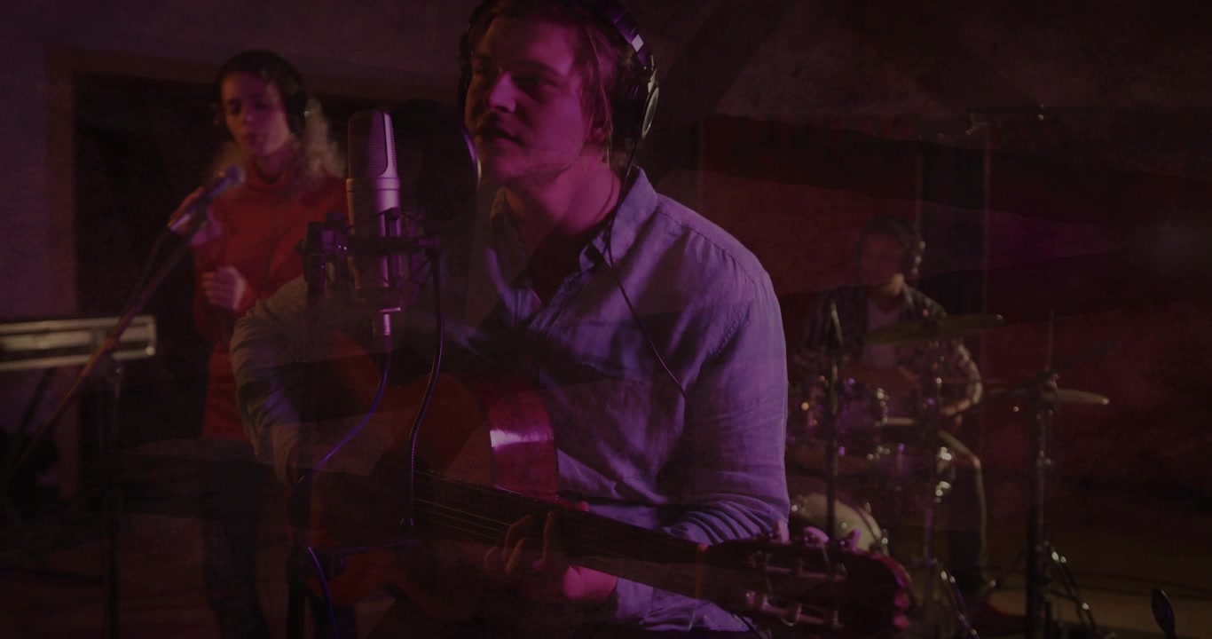 Lead singer-guitarist playing acoustic guitar, singing for recording, cam revealing ghosting band