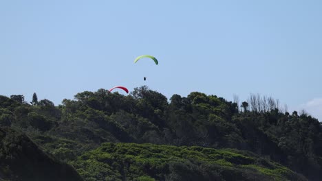 multiple paragliders flying against a clear sky