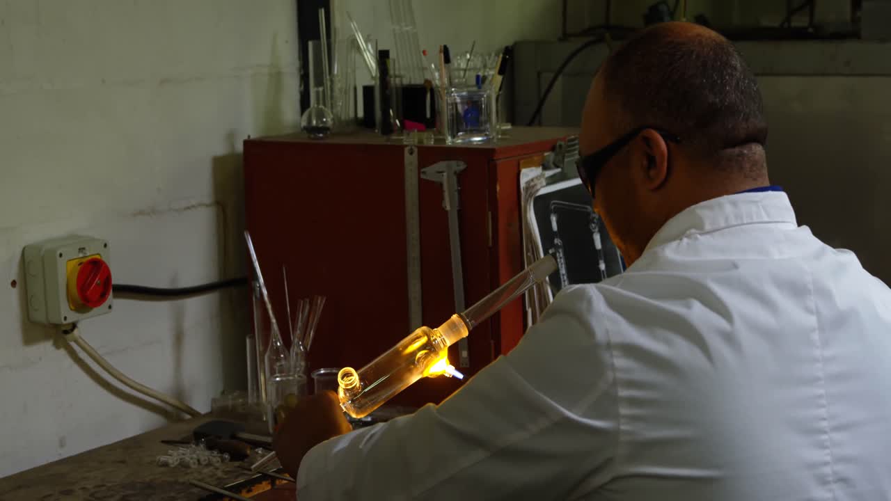 유리 공장에서 유리를  ⁇ 는 성숙한 남성 노동자의 뒷면 4k