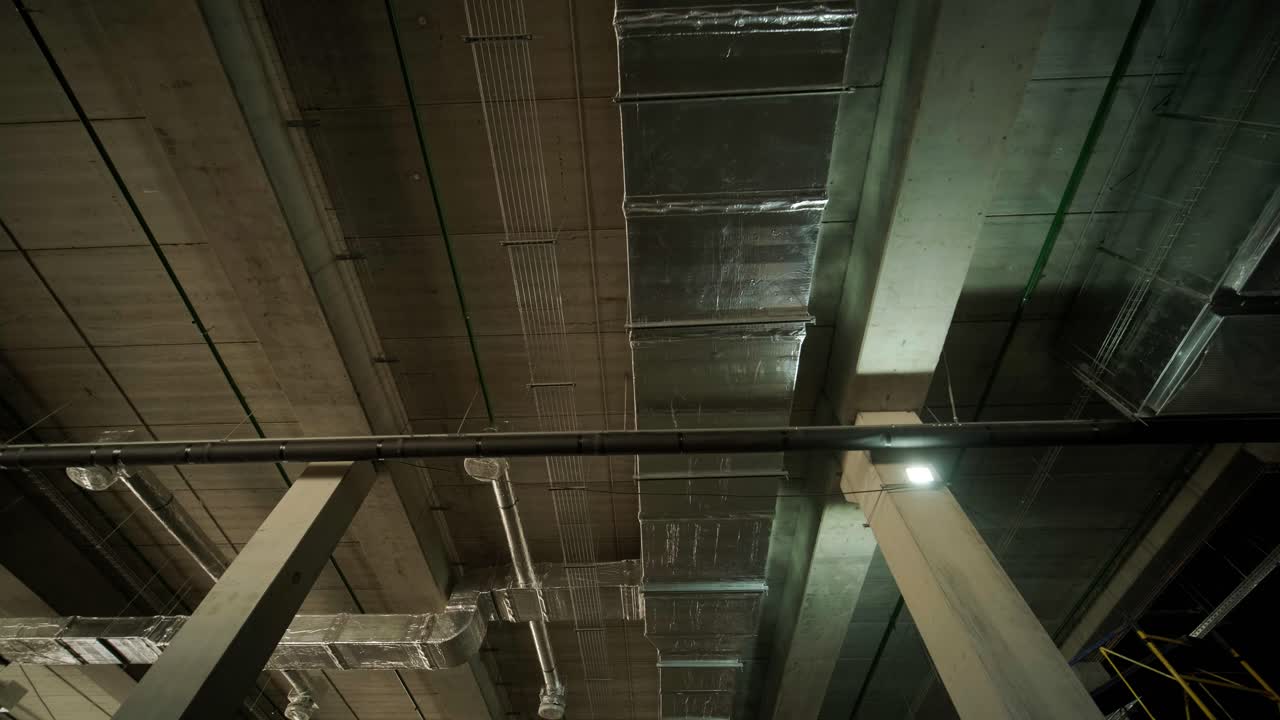 Ventilation pipes in silver insulation material hanging from the ceiling inside new building.