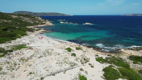 tourist people relax and swim at white sandy beach at la maddalena island, sardinia - aerial 4k
