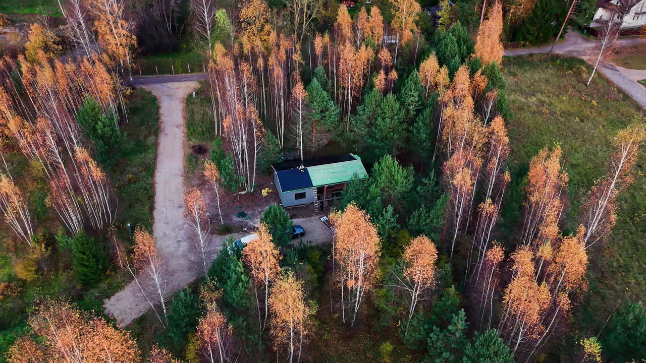 Drone flyver væk fra en charmerende træhytte på en livlig efterårsdag