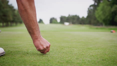 close up of mature male golfer placing golf ball on tee