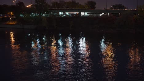 Schöne-Stadtlichter,-Die-Sich-Im-Fluss-Entlang-Der-Brücke-Spiegeln