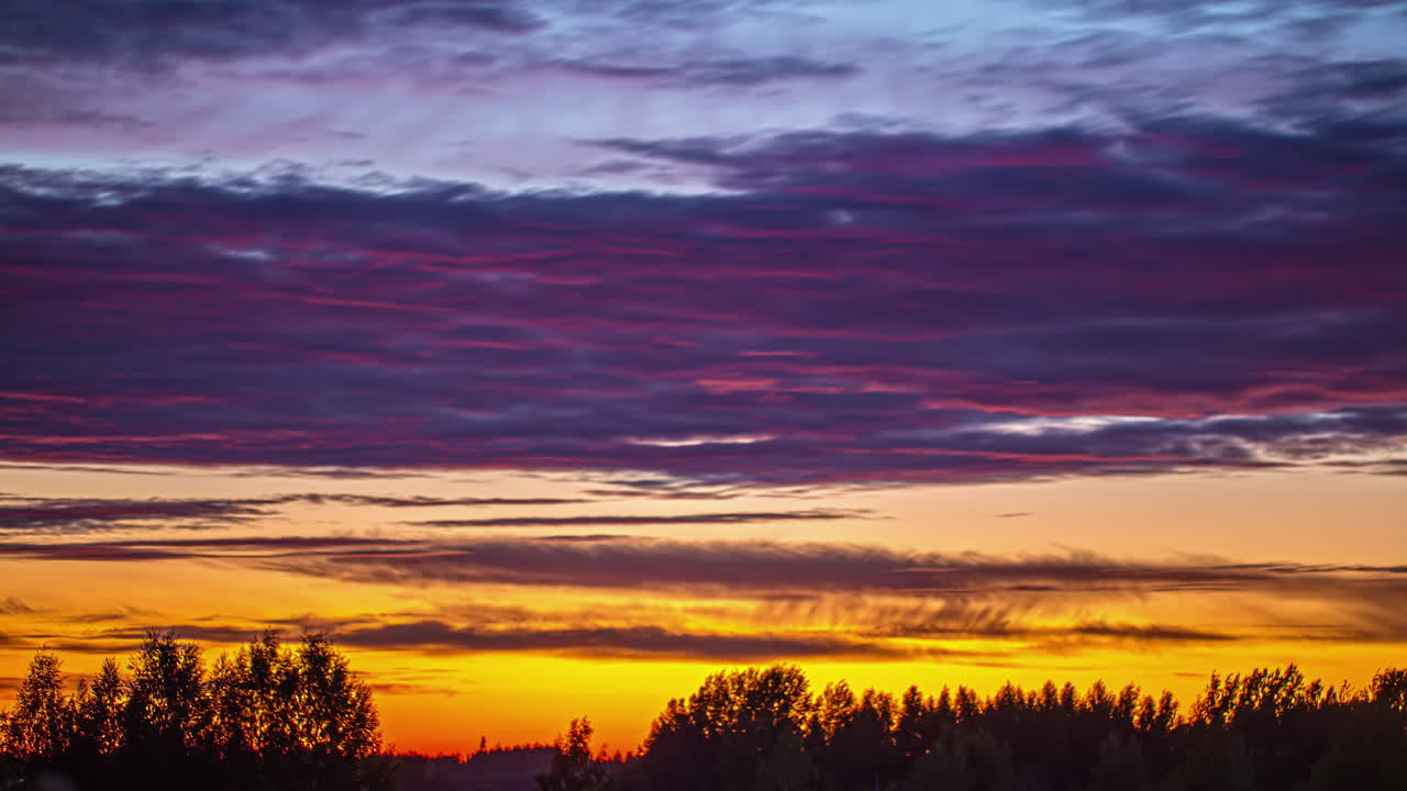 un colorido paisaje de nubes al atardecer sobre un bosque - lapso de tiempo