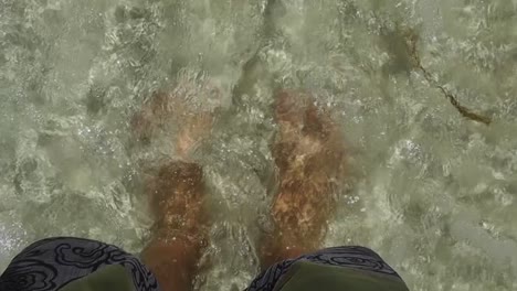 la práctica de la atención plena y la meditación de un joven varón relajándose descalzo en la arena y siendo bañado por aguas cristalinas del océano