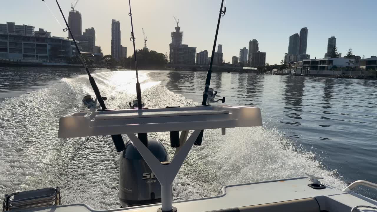 Un motoscafo ad alta velocità crea una scia bianca mentre naviga verso lo skyline della Gold Coast