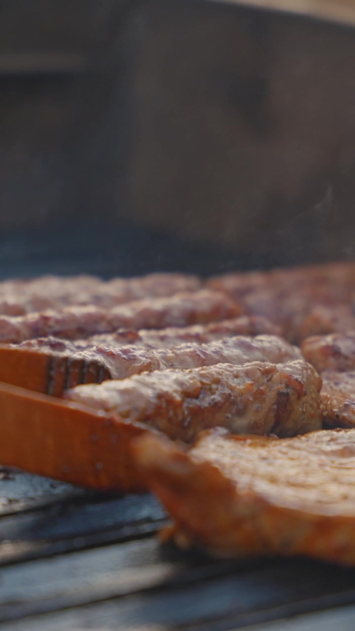 Carne sfrigolante che cuoce su una griglia in un video verticale ravvicinato, con fumo che sale e illuminazione dorata—perfetto per reel mobili e creatori di contenuti culinari.