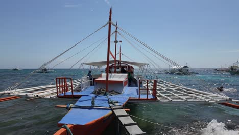 oslob, isla de cebu, filipinas - el tradicional barco filipino, listo y esperando a la tripulación de viaje en oslob, isla del cebu, filipinas, contra un telón de fondo de cielo azul claro