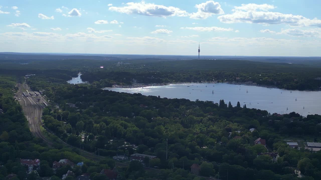 Wannsee lakes surrounded by lush green forest on sunny day with blue sky and clouds. Gorgeous aerial view flight rotation to right drone