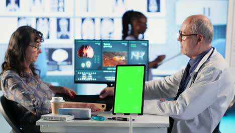 vertical video senior medic talking to his female patient next to mockup green screen