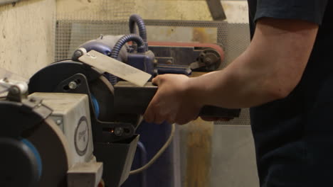 worker grinding steel on a bench grinder, close up