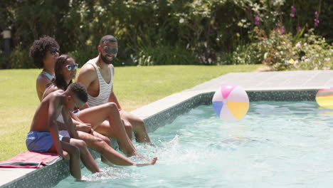 African-american-parents,-son-and-daughter-sitting-in-sun-with-feet-in-pool,-copy-space,-slow-motion