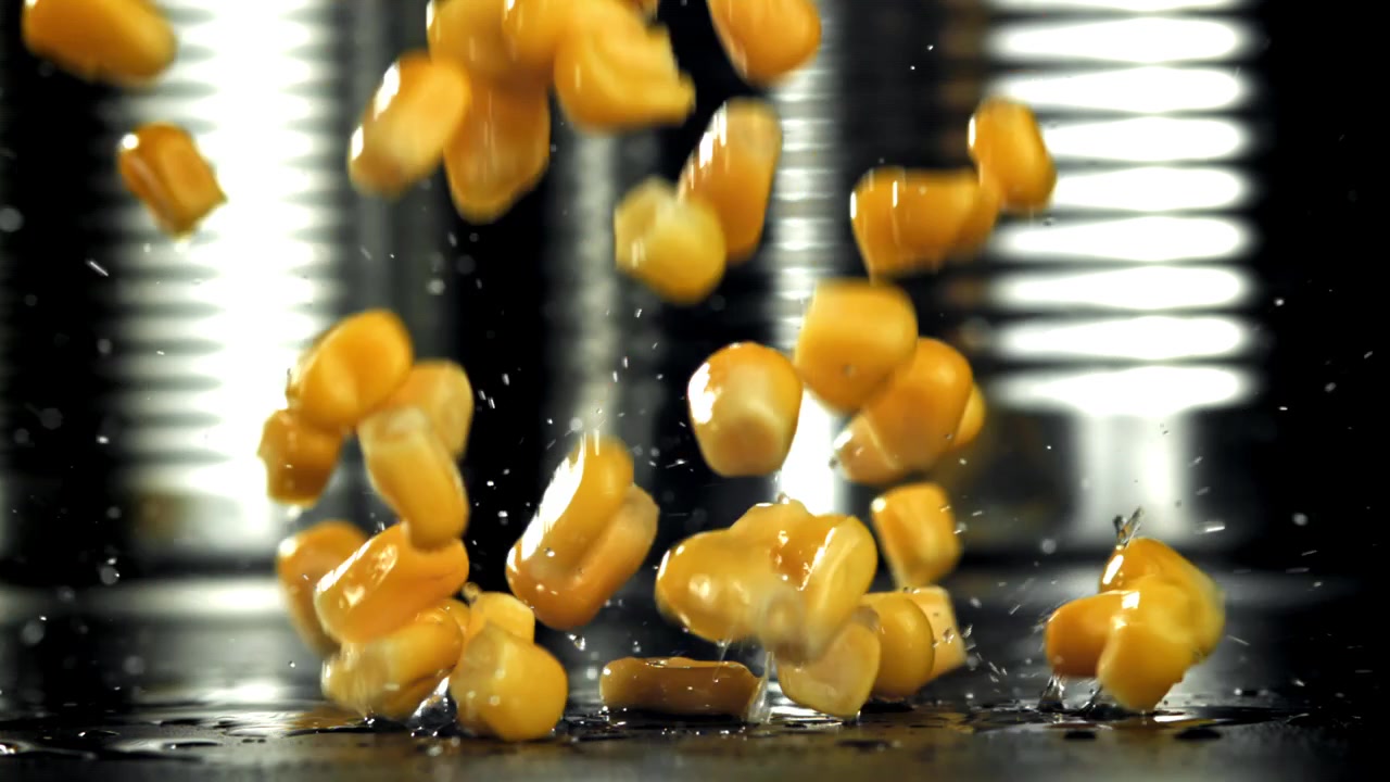 Fresh Corn Kernels Dropping onto a Wet Surface in Slow Motion