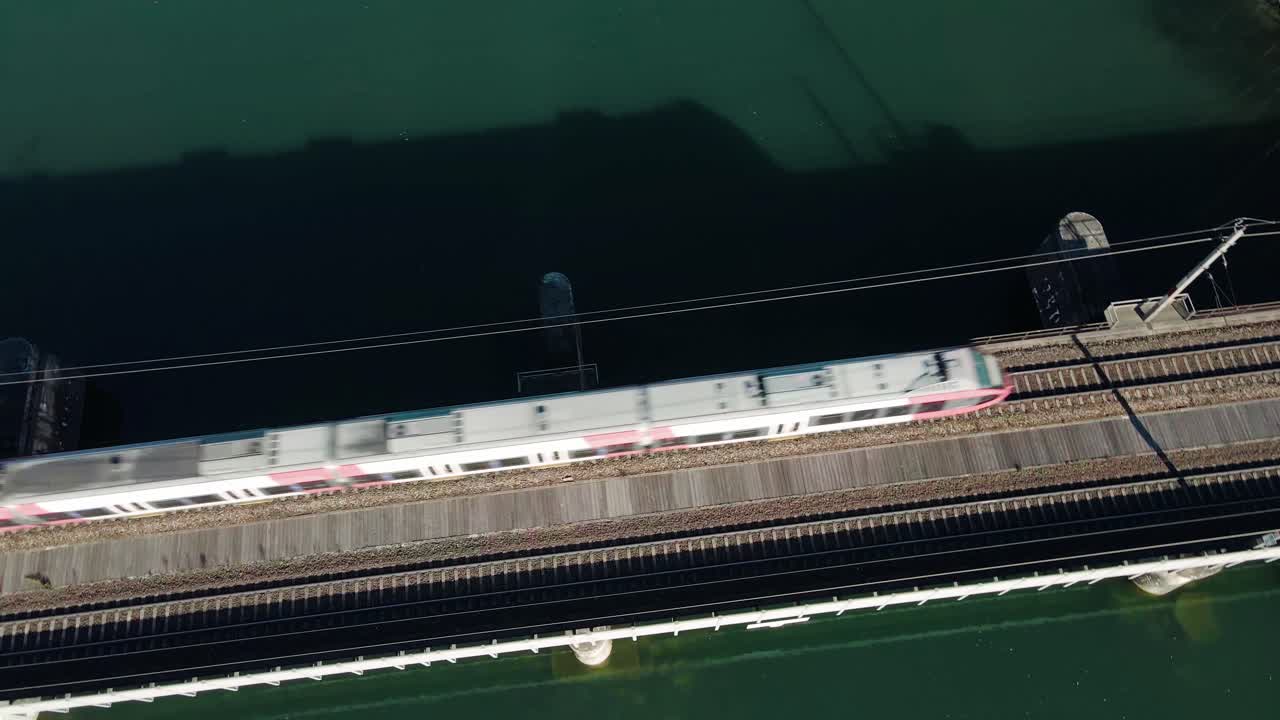 드론으로 촬영된 철도 교량을 통해 아름다운 강을 건너는 지역 열차가 열차와 함께 천천히 회전하고 회전합니다.