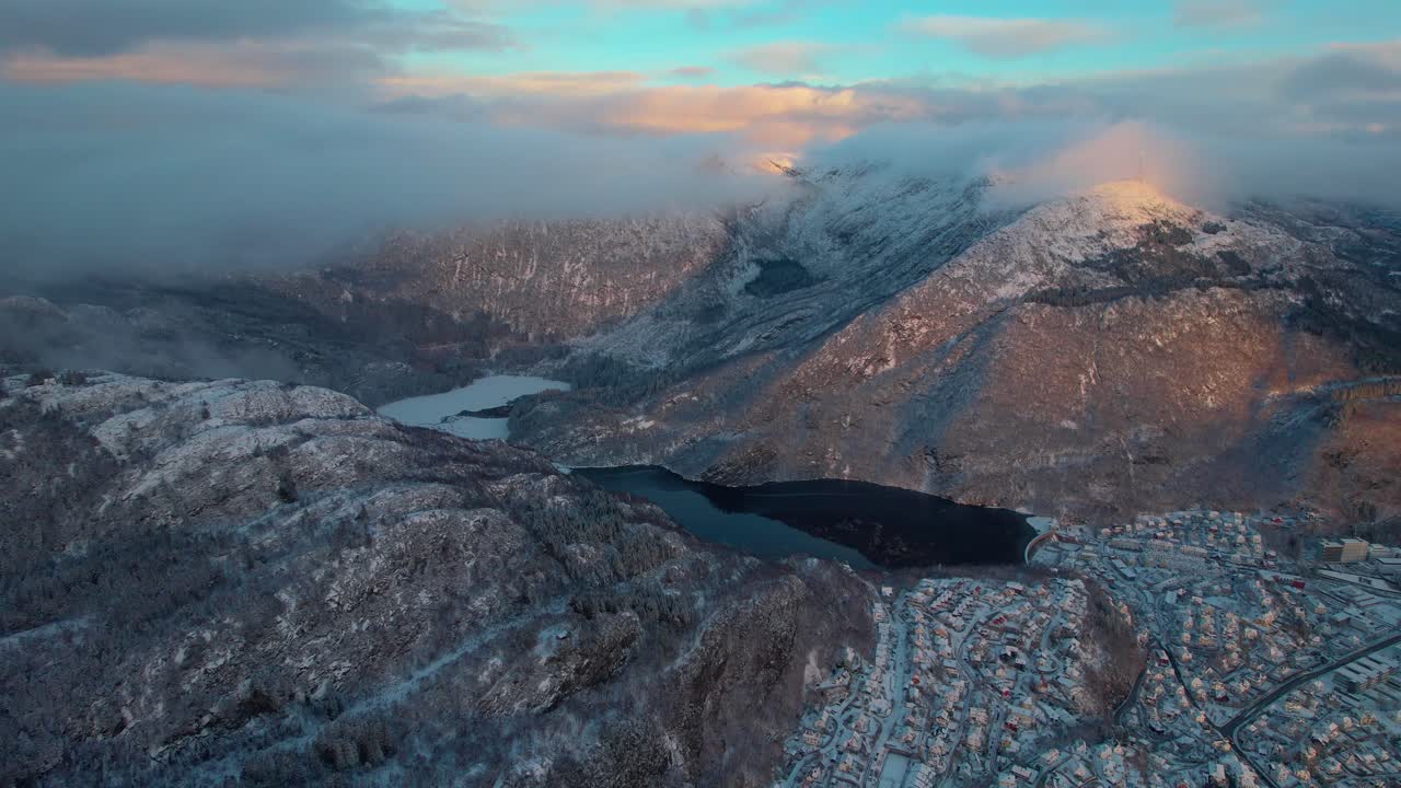 Bergen Drone aerial, Golden hour winter landscape above city and snowymountains, Norway, Scandinavian fjords in Arctic area