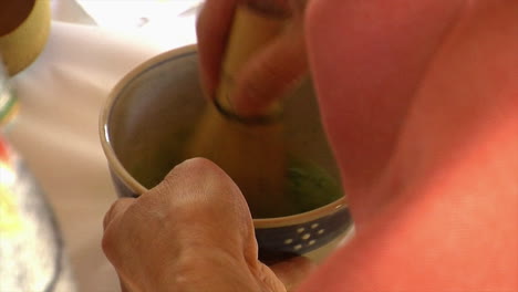 primer plano de batidor de bambú revolviendo té matcha en un tazón de té de estilo japonés