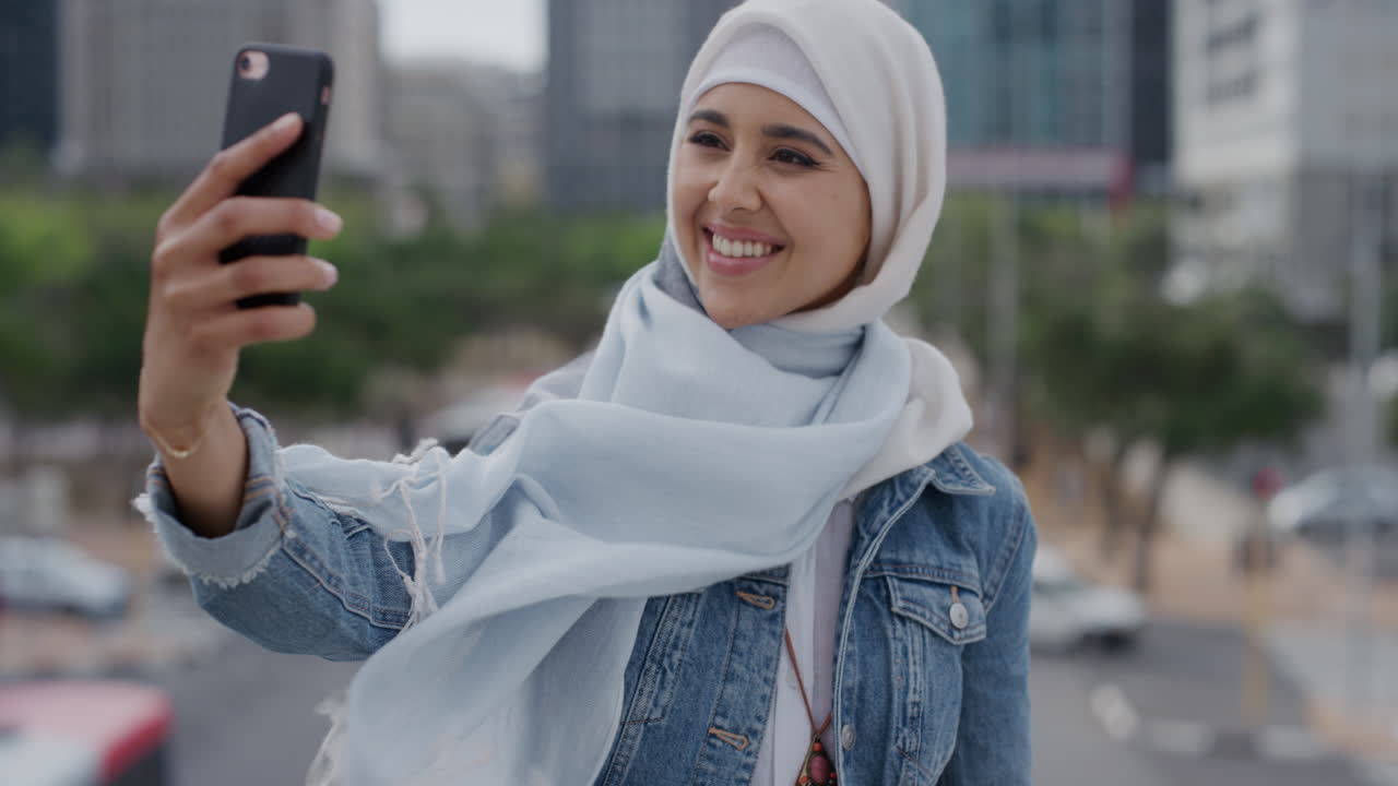 portrait young happy muslim woman using smartphone taking selfie photo posing in city enjoying urban travel sharing experience wearing hijab headscarf modern lifestyle