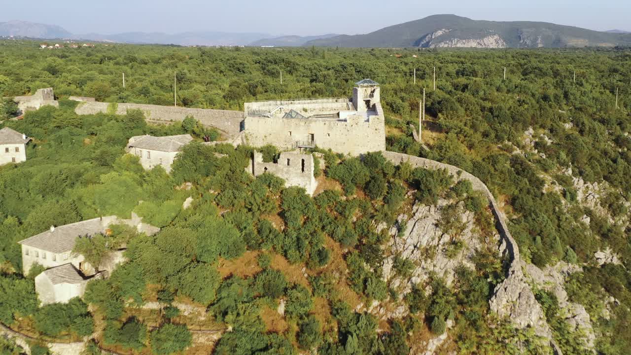 High aerial drone approaching view of Pocitelj castle and over the rooftop